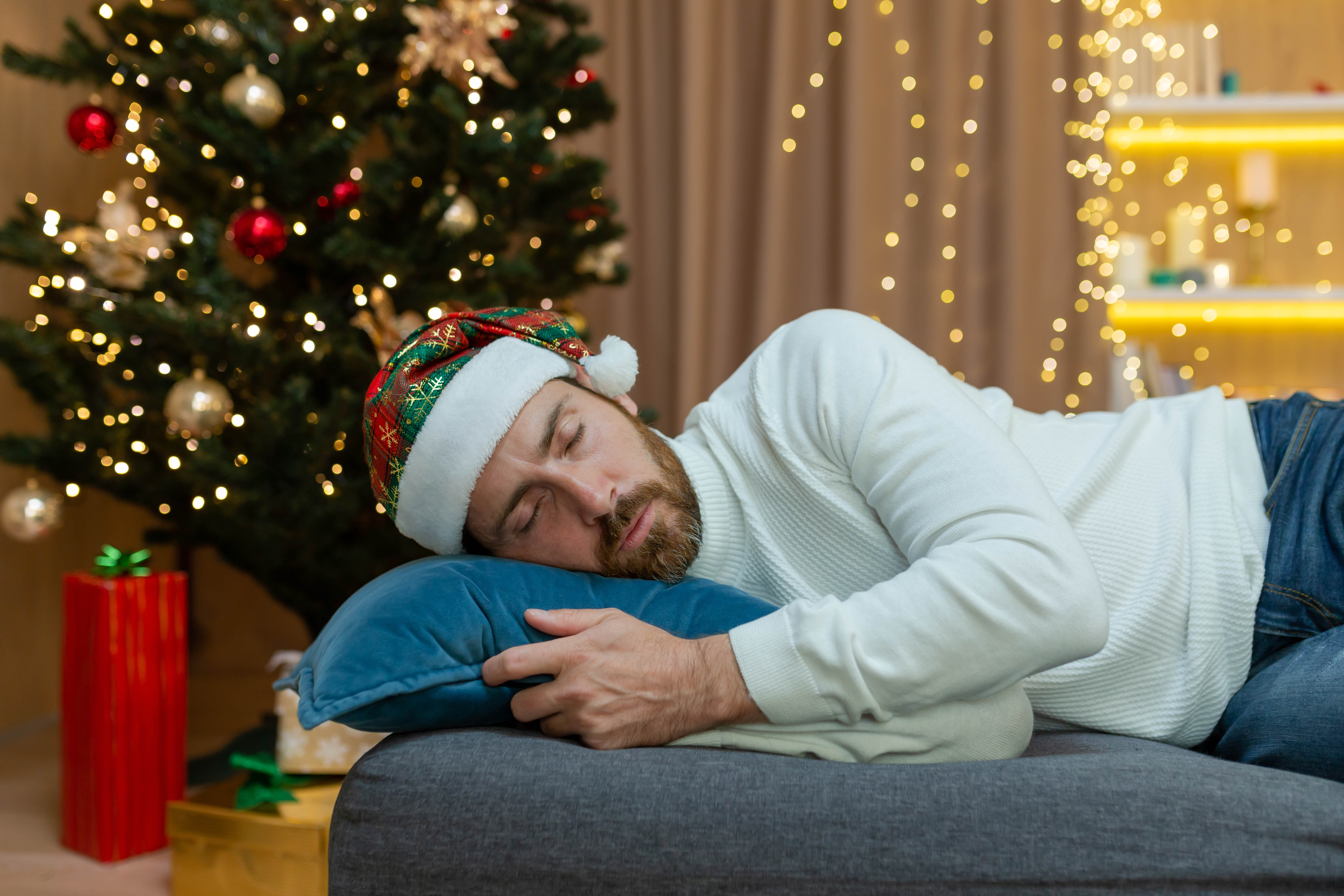 Man sleeping on the couch with the Christmas tree in the background